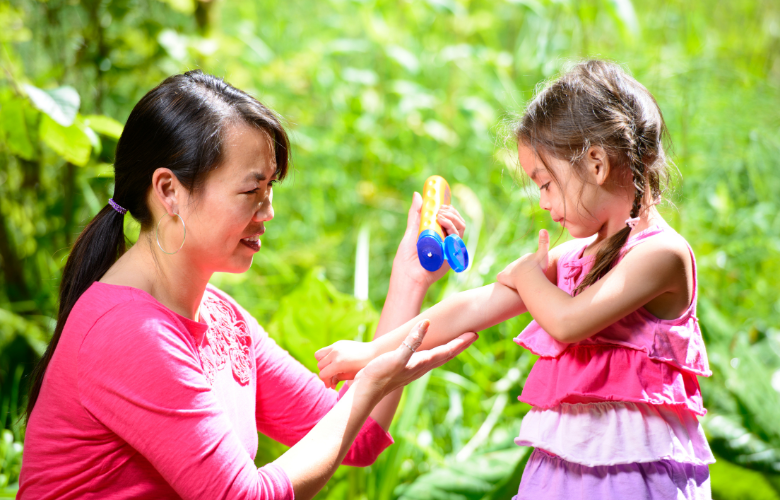Asian mother putting sunscreen on young daughter